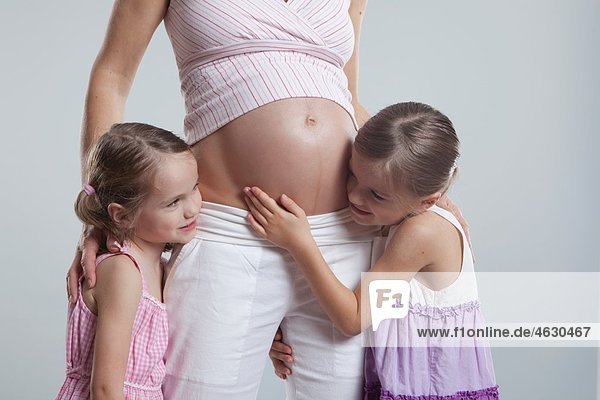 Töchter umarmen schwangere Mutter