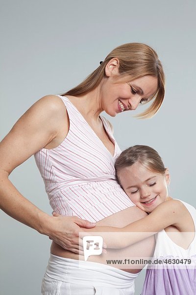 Tochter umarmt schwangere Mutter