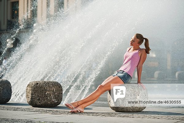 Junge Frau am Brunnen sitzend
