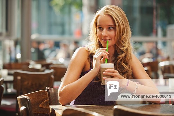 Teenage girl drinking coffee in cafe  smiling
