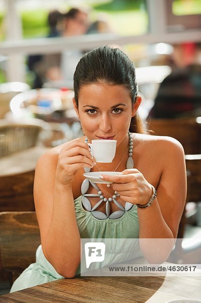 Young woman drinking coffee in cafe  smiling  portrait