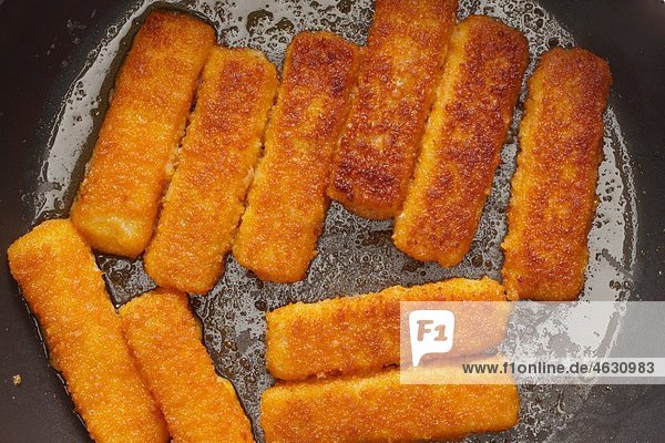 Fish fingers frying in a pan  close up