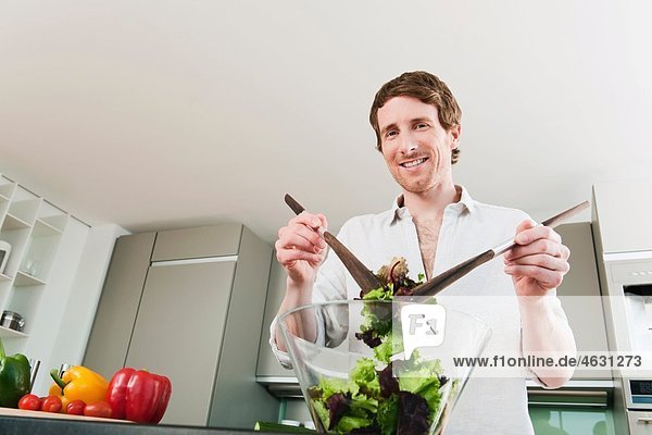 Mann in der Küche beim Mischen von Gemüse