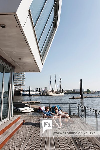 Germany  Hamburg  Couple relaxing in deck chair on floating home