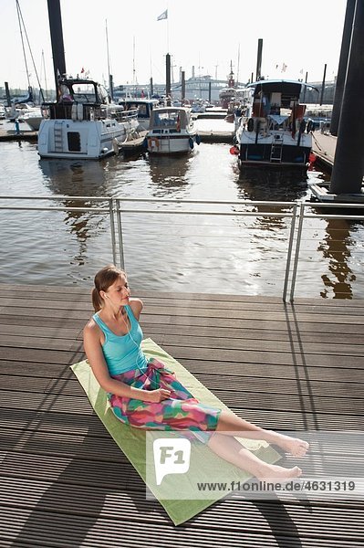 Woman sitting on sun deck and listening to music