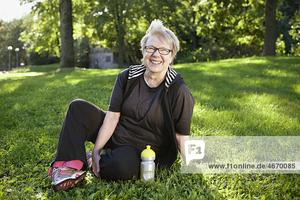 Glückliche Frau auf dem Rasen sitzend