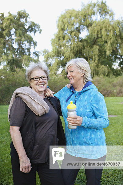 Zwei Frauen  die lächeln und Wasserflasche halten