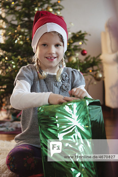 Mädchen mit Weihnachtshut mit großem grünen Geschenk