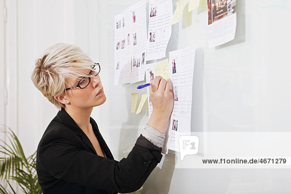Woman writing on paper that hangs on wall