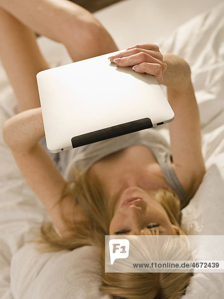 Young woman with Tablet PC in bed