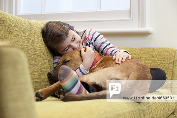 Young girl cuddling her dog on the sofa