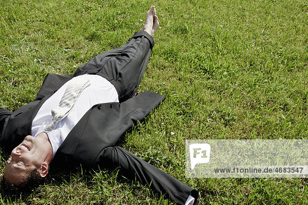 Barfuß Geschäftsmann auf Gras liegend