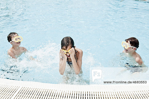 Boys splashing girl in swimmingpool