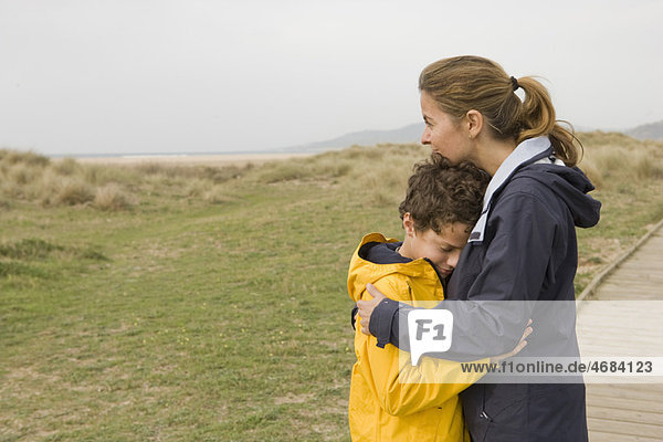 Mutter und Sohn umarmen sich an der Strandpromenade