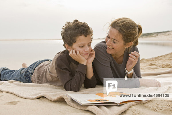 Mutter und Sohn beim Lesen am Strand