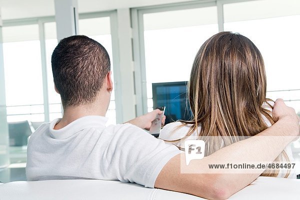 Back view of a couple watching TV at home