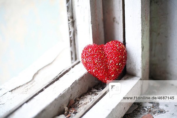 loneliness concept - red heart on white obsolete windowsill