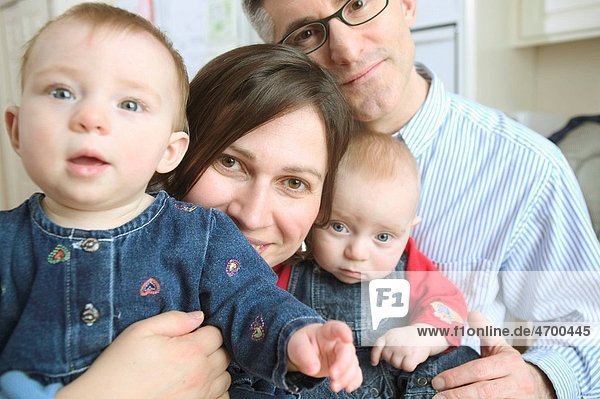 Portrait of a mother and father with twin babies.