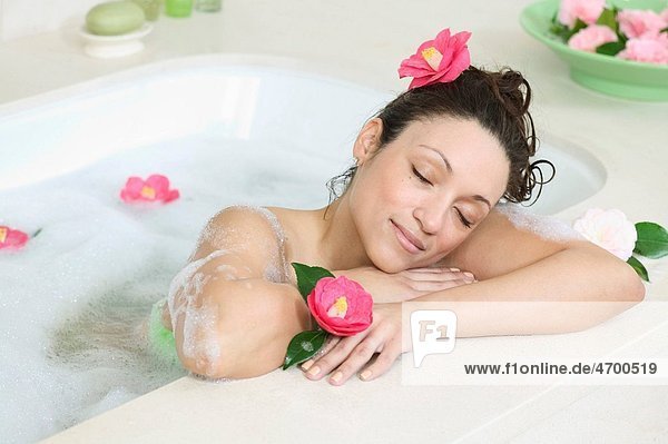 A woman relaxes in a bathtub full of bubbles.