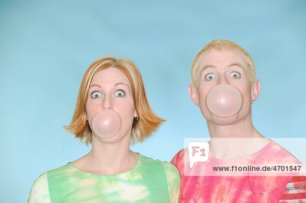 Young couple blowing bubbles with bubblegum