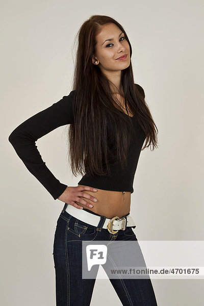 Young woman with long brown hair  black top and blue jeans posing