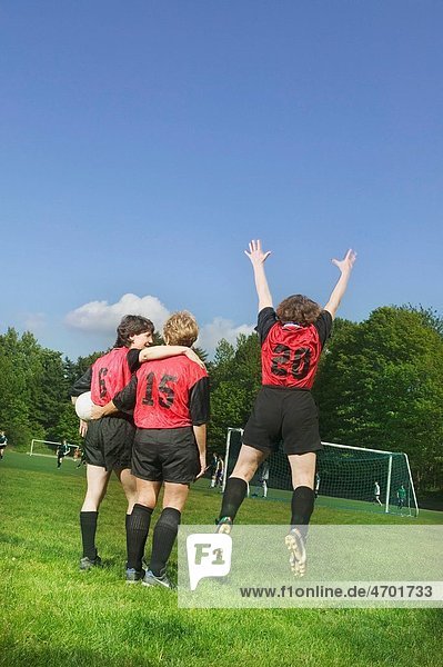 Three female soccer players celebrate a win