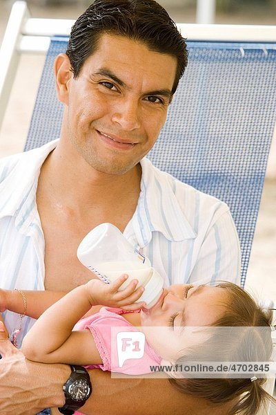 Portrait of father holding daughter with bottle