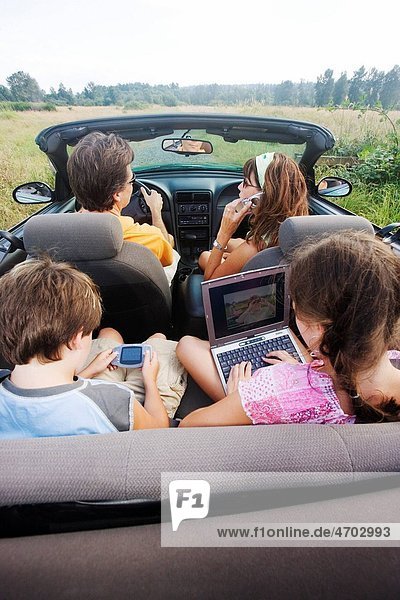 Family in convertible using portable electronics