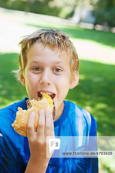 Portrait of boy eating hamburger outside