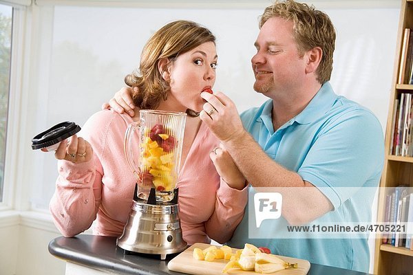 Couple eating fruit while making a smoothie