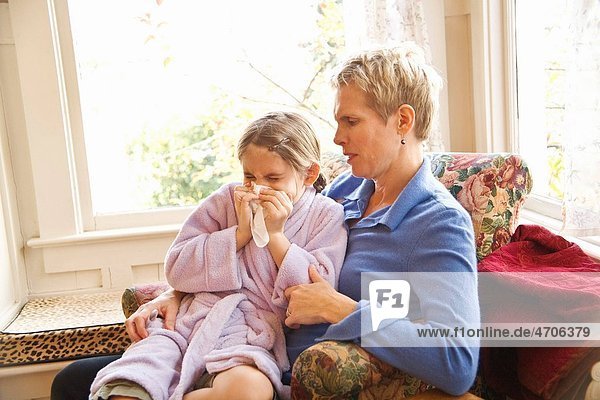 Mother watching sick daughter blow nose