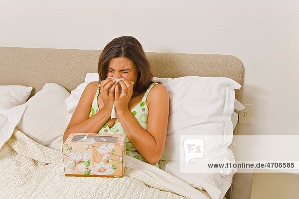 Woman blowing nose in bed