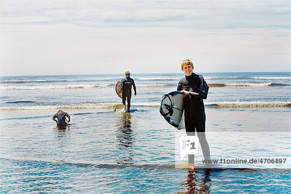 Surfers holding surfboards on the beach Washington State USA