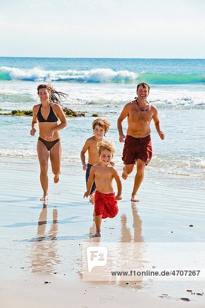 family running on beach in mexico