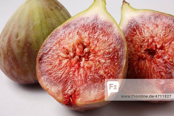 Fruit   Figs Ficus Carica Anjir one full and other cut in two half red juicy texture on white background
