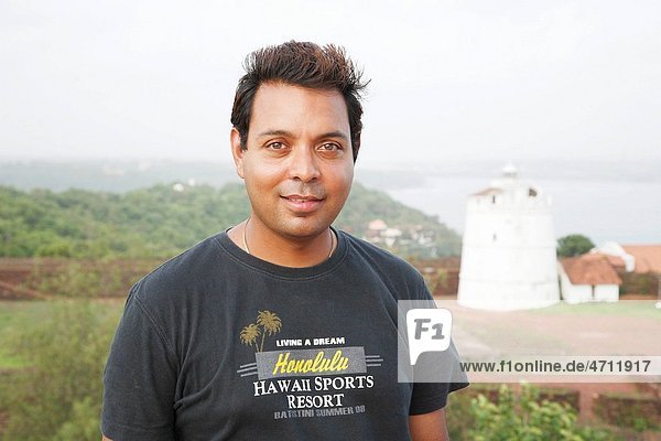 Man smiling   Lighthouse of Fort Aguada in background   Goa   India MR468