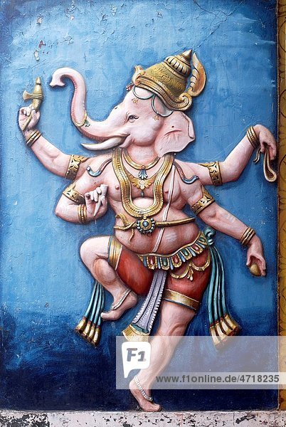 Colourfully painted relief of dancing lord Ganesh Ganpati on wall of temple