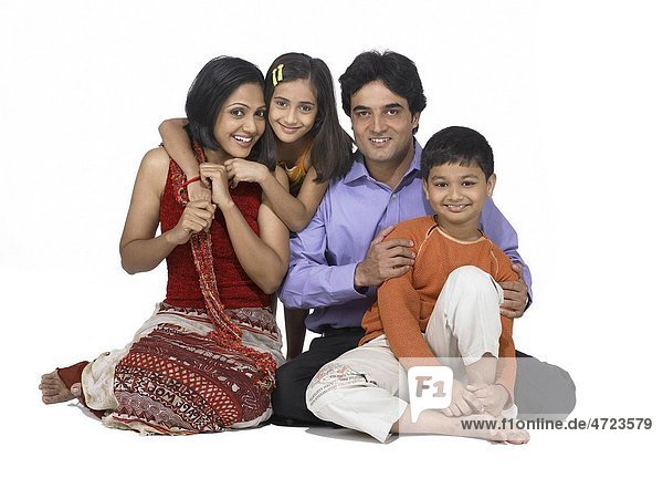 South Asian Indian family with father mother son and daughter sitting smiling and looking at camera MR 698   699   700   701