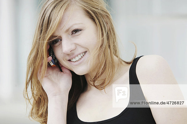 Junge Frau telefoniert mit dem Handy  lächelnd