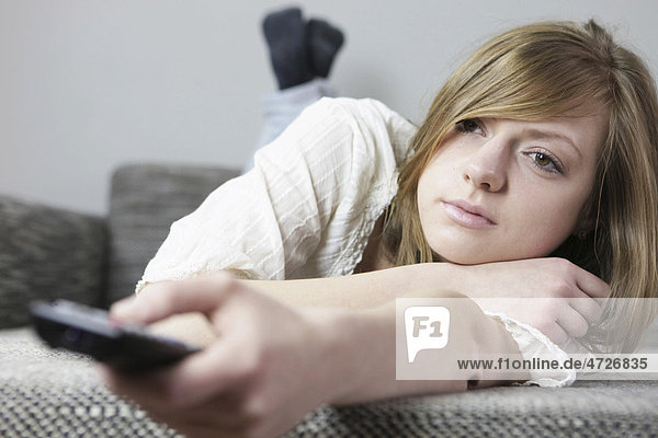 Young woman on the couch with remote in her hand