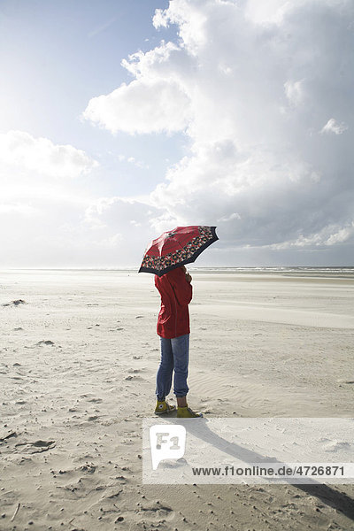 Frau mit Regenschirm am Strand  Wind  Gewitterwolke  Insel Langeoog  Ostfriesische Inseln  Nordsee  Deutschland  Europa