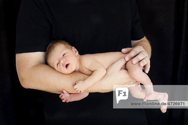 Neugeborenes Baby  zwei Wochen  auf dem Arm des Vaters