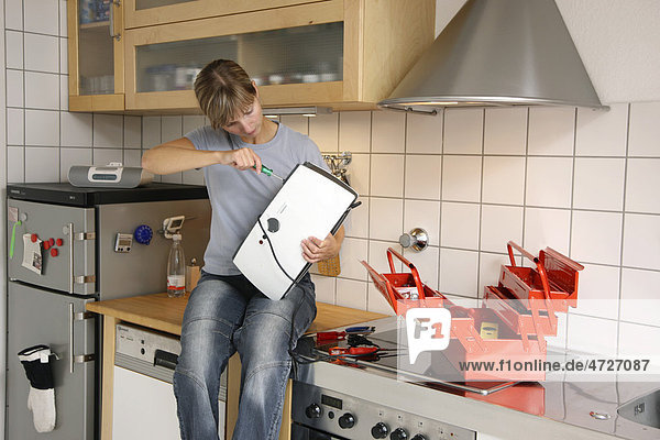 Junge Frau repariert einen Toaster in einer Küche