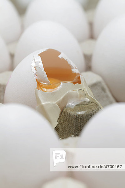 Ein zerbrochenes Ei und ganze Eier in Eierkarton
