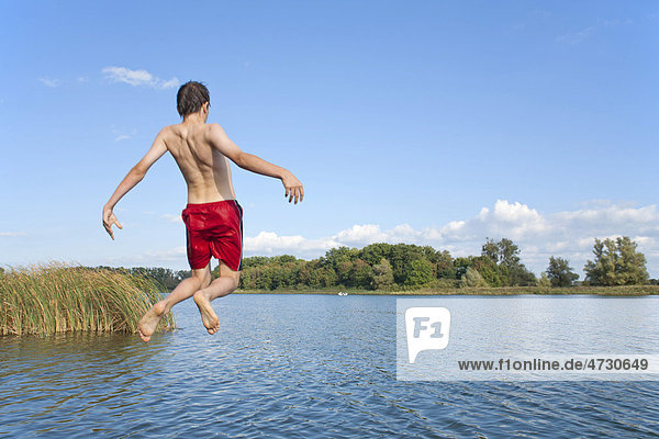 Boy jumping off a bridge into a lake  Teterow  Mecklenburg-Western Pomerania  Germany  Europe