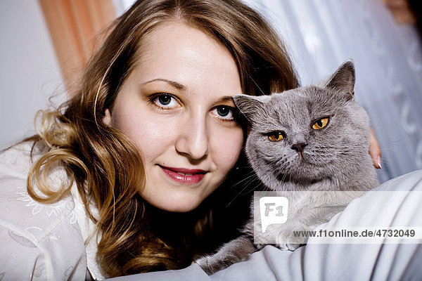 Junge Frau mit Katze im Schlafzimmer