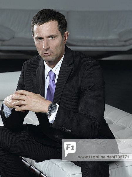 Businessmann im Anzug sitzend auf weißem Sofa