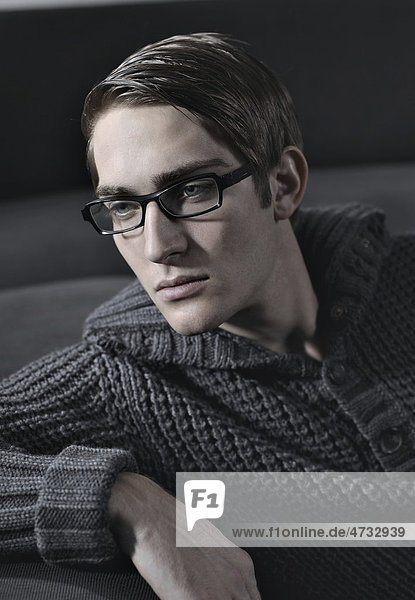 Young man wearing glasses sitting on a sofa