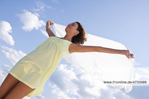 Junge Frau hält Schal gegen Himmel