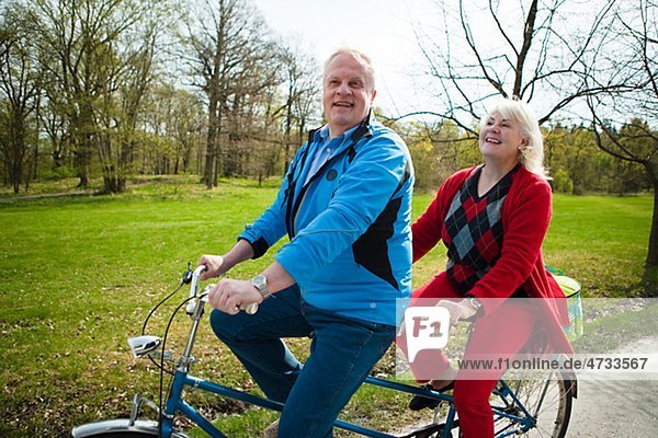 Senior couple riding on tandem bicycle